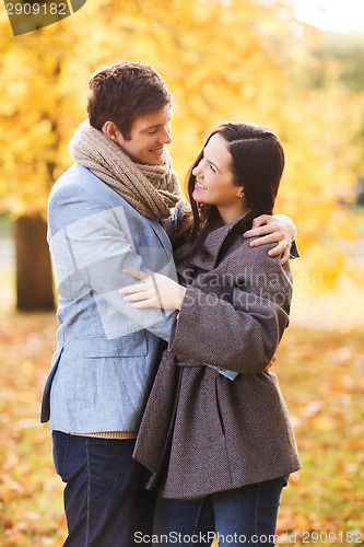 Image of smiling couple hugging in autumn park