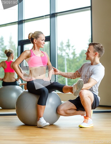 Image of smiling man and woman with exercise ball in gym