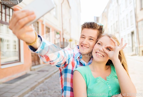 Image of smiling couple with smartphone in city