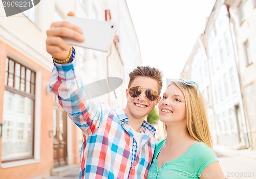 Image of smiling couple with smartphone in city