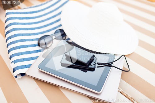 Image of close up of tablet pc and smartphone on beach