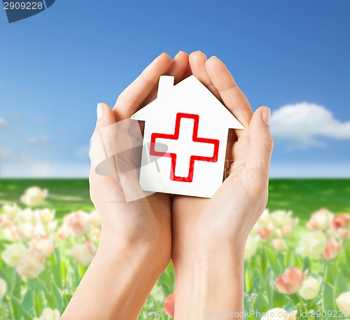 Image of hands holding paper house with red cross