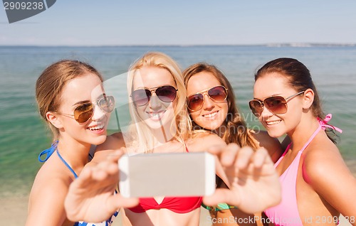 Image of group of smiling women making selfie on beach