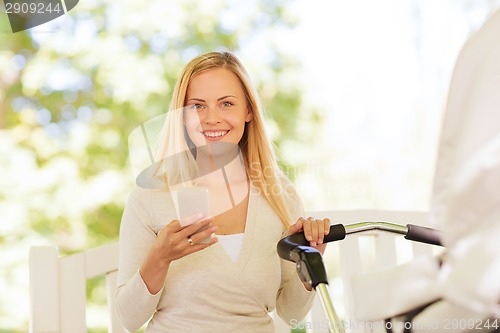 Image of happy mother with smartphone and stroller in park