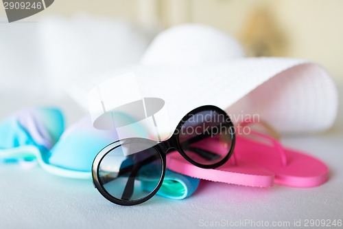 Image of bikini top, hat, flip-flop and sunglasses