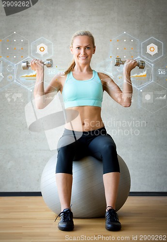 Image of smiling woman with dumbbells and exercise ball