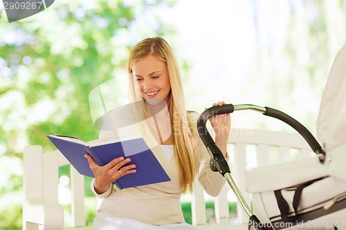 Image of happy mother with book and stroller in park