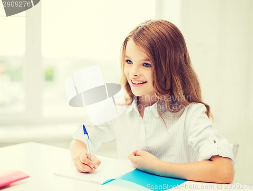 Image of student girl writing in notebook at school