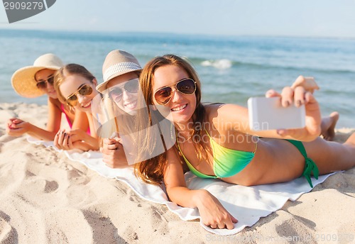 Image of group of smiling women with smartphone on beach