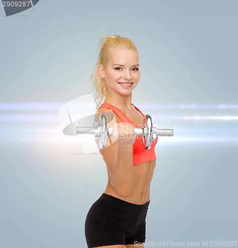 Image of young sporty woman with heavy steel dumbbell