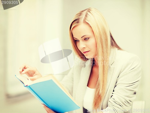 Image of young woman reading book at school