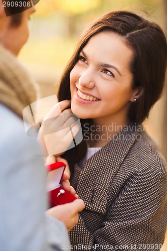 Image of close up of smiling couple with gift box in park