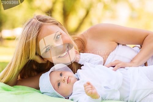 Image of happy mother lying with little baby on blanket