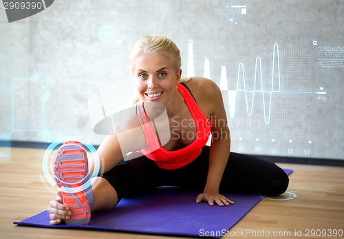 Image of smiling woman doing exercises on mat in gym