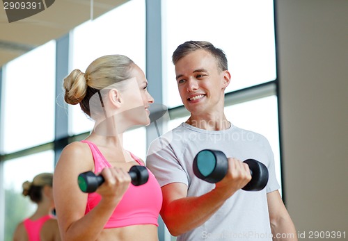Image of smiling young woman with personal trainer in gym