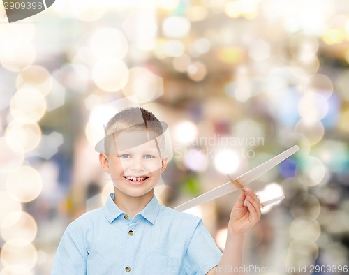 Image of smiling little boy holding a wooden airplane model