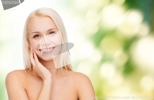 Image of smiling young woman touching her face skin