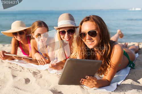 Image of group of smiling young women with tablets on beach