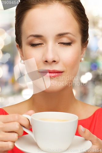 Image of smiling woman in red dress with cup of coffee