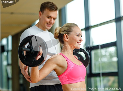 Image of smiling man and woman with barbell in gym