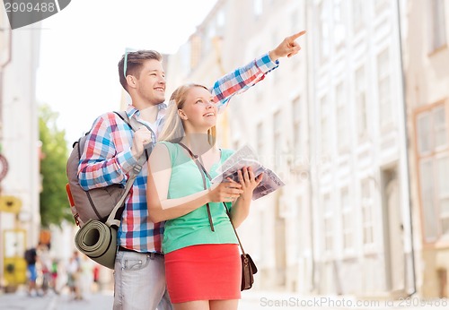 Image of smiling couple with city guide and backpack