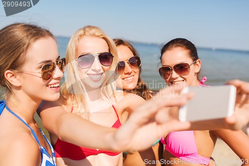 Image of group of smiling women making selfie on beach