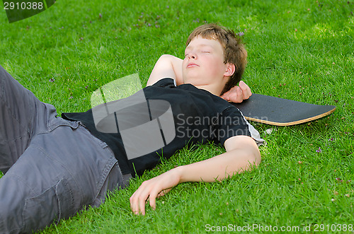 Image of Teenager with skate resting on grass