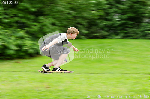 Image of Young teen guy fast rides a skateboard in park