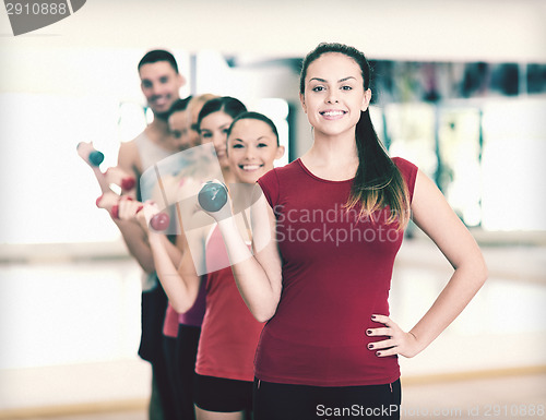 Image of group of smiling people with dumbbells in the gym