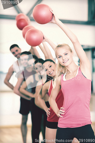 Image of group of smiling people working out with ball