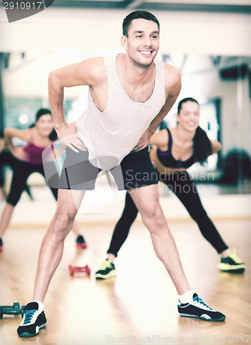 Image of smiling male trainer working out in the gym