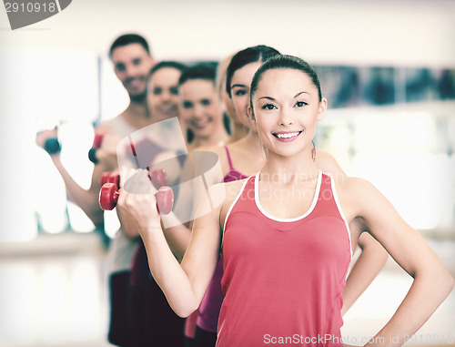 Image of group of smiling people with dumbbells in the gym
