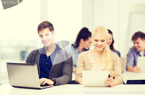 Image of two smiling students with laptop and tablet pc