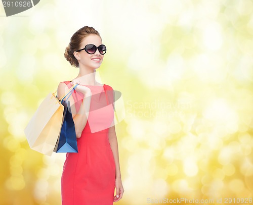Image of smiling elegant woman in dress with shopping bags