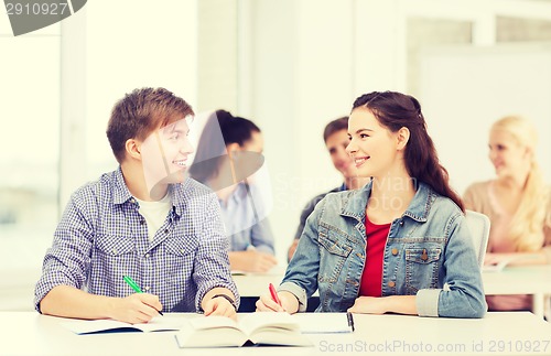 Image of two teenagers with notebooks and book at school