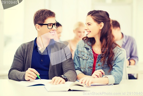 Image of two teenagers with notebooks and book at school