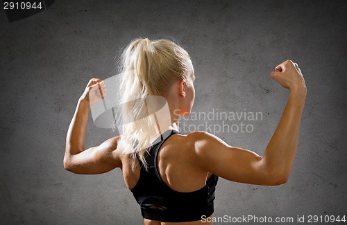 Image of sporty woman from the back flexing her biceps