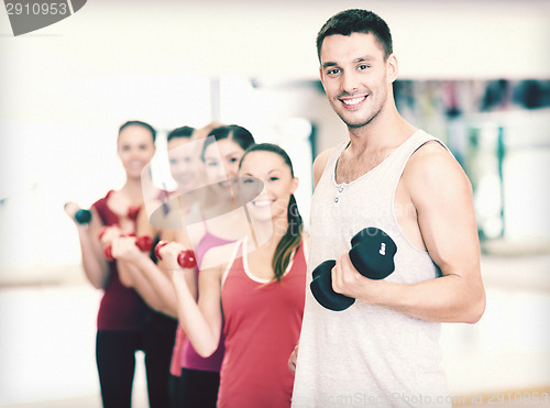 Image of group of smiling people with dumbbells in the gym