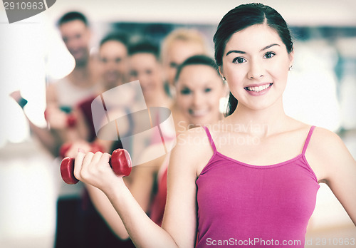 Image of group of smiling people with dumbbells in the gym