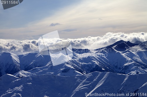 Image of Evening snowy mountains and sunlight clouds