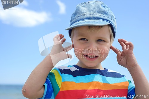 Image of Small boy holds his hands over ears not to hear