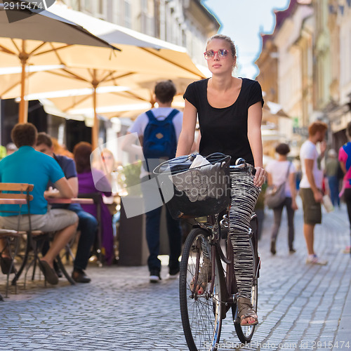 Image of Woman riding bicycle in city center.