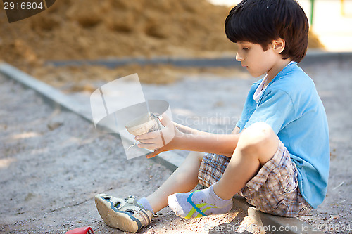Image of boy shakes the sand out of the shoe