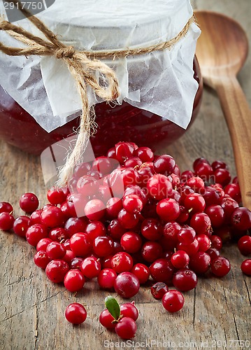 Image of fresh raw cowberries and jar of jam