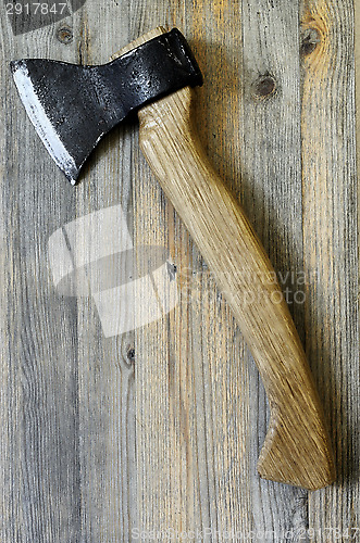 Image of ax with oak handle on a wooden background, vertical
