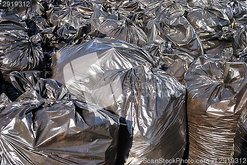 Image of pile of black garbage bags with tons of trash, horizontal