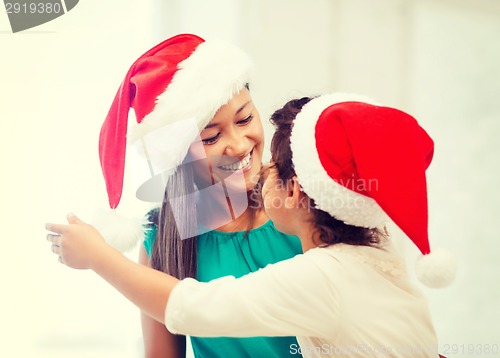 Image of hugging mother and daughter in santa helper hats