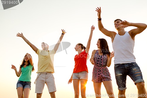 Image of smiling friends dancing on summer beach