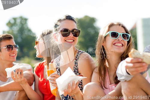 Image of group of smiling friends sitting on city square