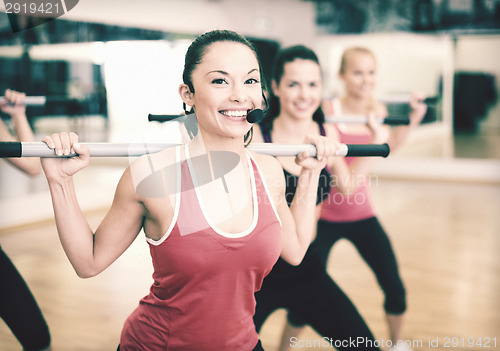 Image of group of smiling people working out with barbells